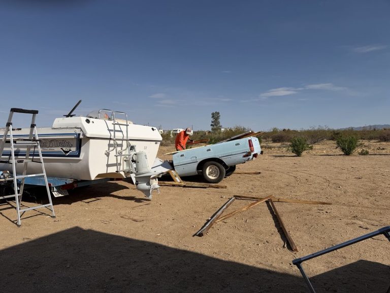 Yukon Delta 25 on its trailer beside a pickup truck during the cabin rebuild
